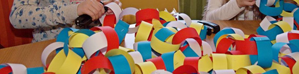 kleuters knutselen een papieren slinger in elkaar