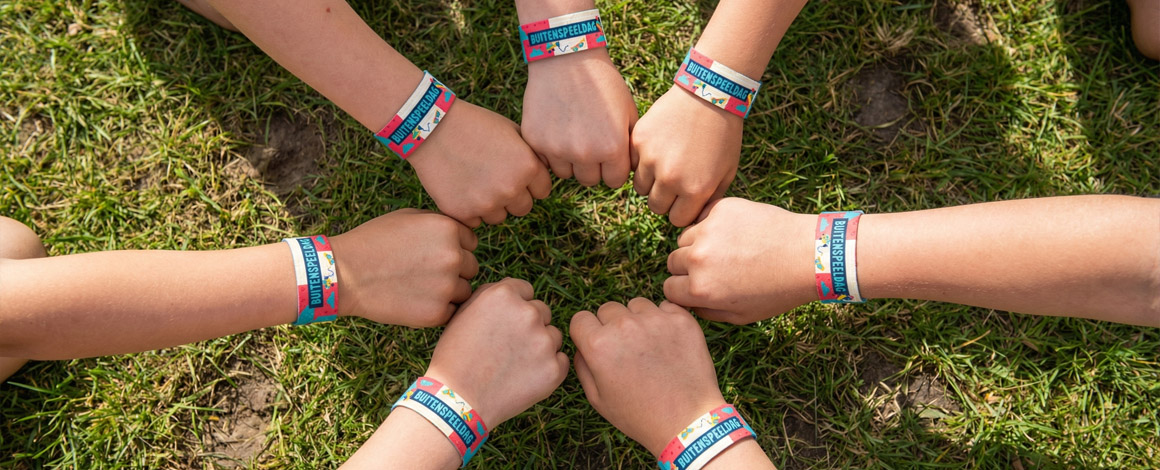 kinderen met hun polsen naar elkaar terwijl ze een polsbandjes dragen als aandenken voor Buitenspeeldag