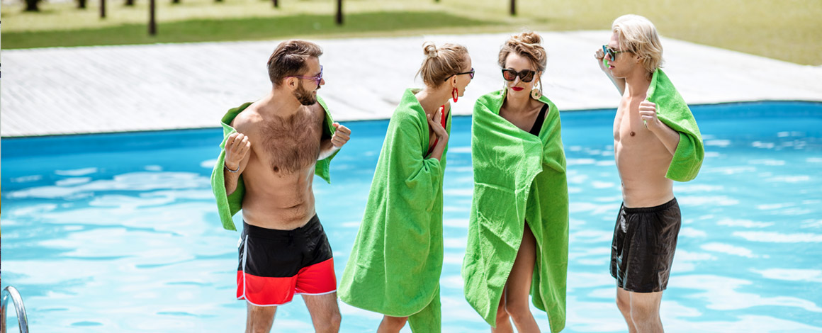 2 koppels aan een zwembad gewikkeld in groene handdoeken